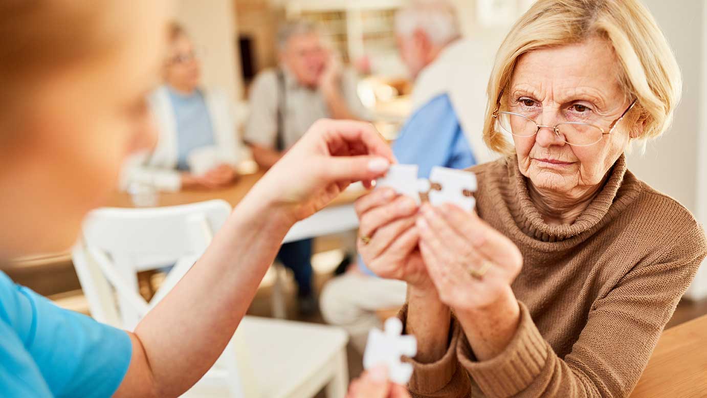 Betreuer kümmert sich um ältere Frau mit Demenz