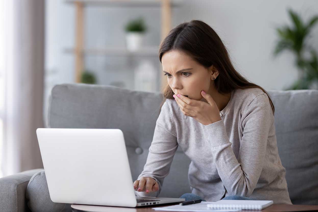 Frau reagiert auf strafbare online Erpressung vor dem Laptop