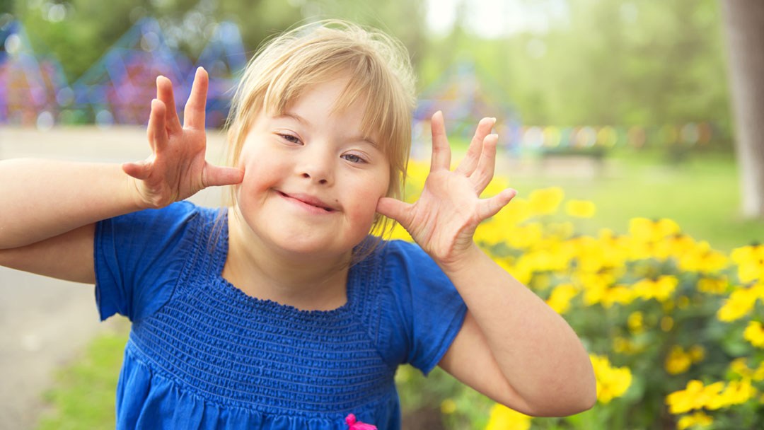 Kind mit Down-Syndrom erhält mit seinen Eltern Frühförderung und lächelt.