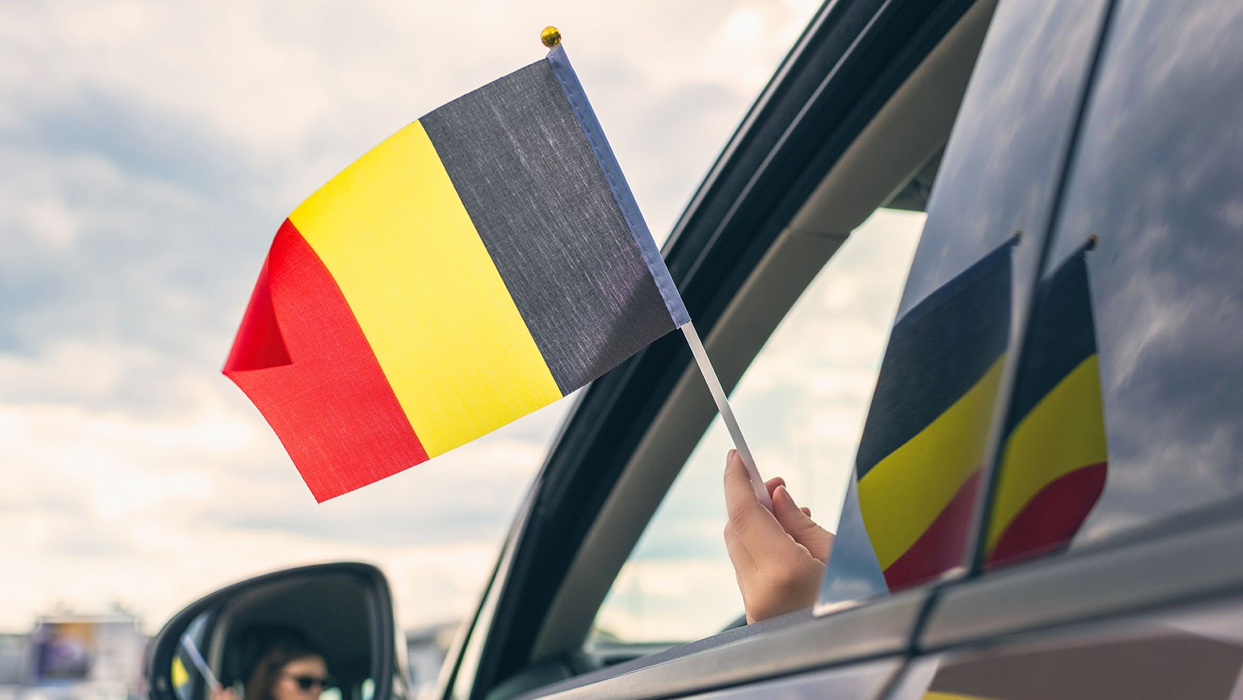 Autofahrerin hält belgische Flagge in der Hand