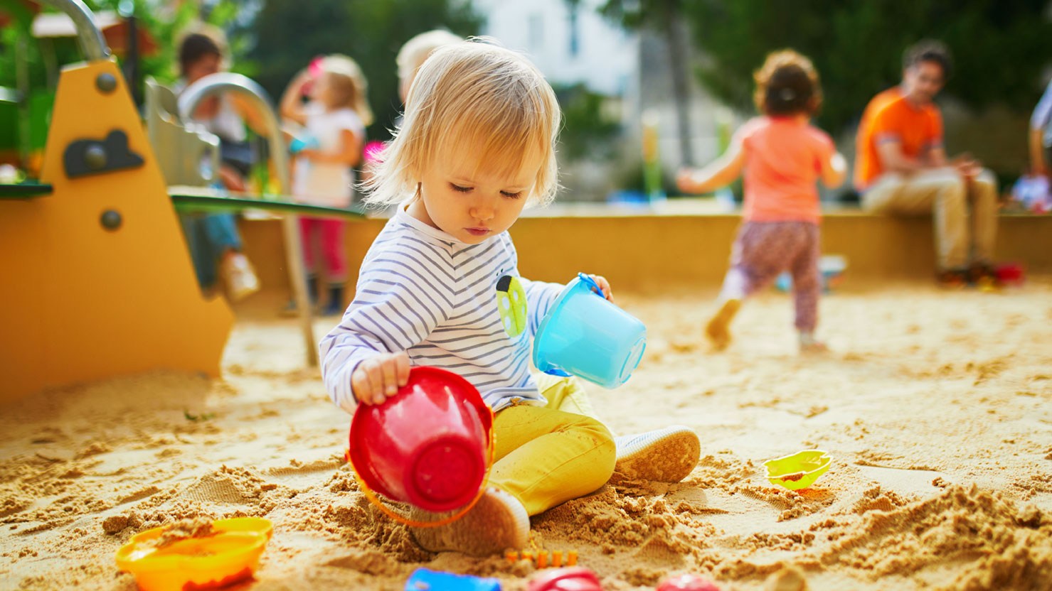 Kinder spielen am Kinderspielplatz während Eltern ihre Aufsichtspflicht wahrnehmen.