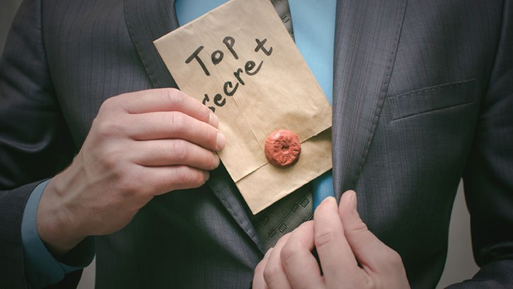 Ein Mann steckt ein Kuvert in sein Sakko, auf dem „Top Secret“ steht.