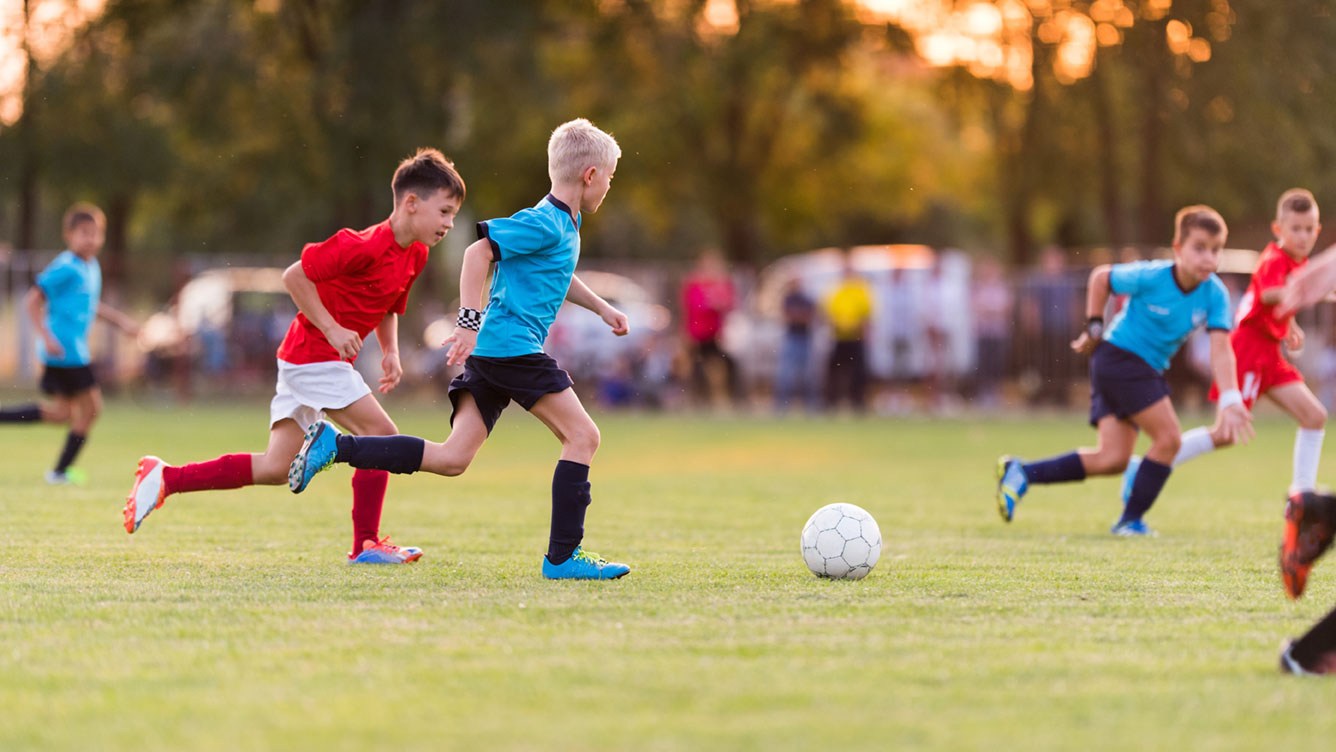 Kinder spielen am Fußballfeld: Sie freuen sich, weil ihre Eltern den Kinderfreibetrag 2022 geltend machen können.