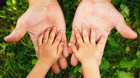 Pflegekind adoptieren: Pflegkind legt seine Hände in die der Pflegeeltern. 