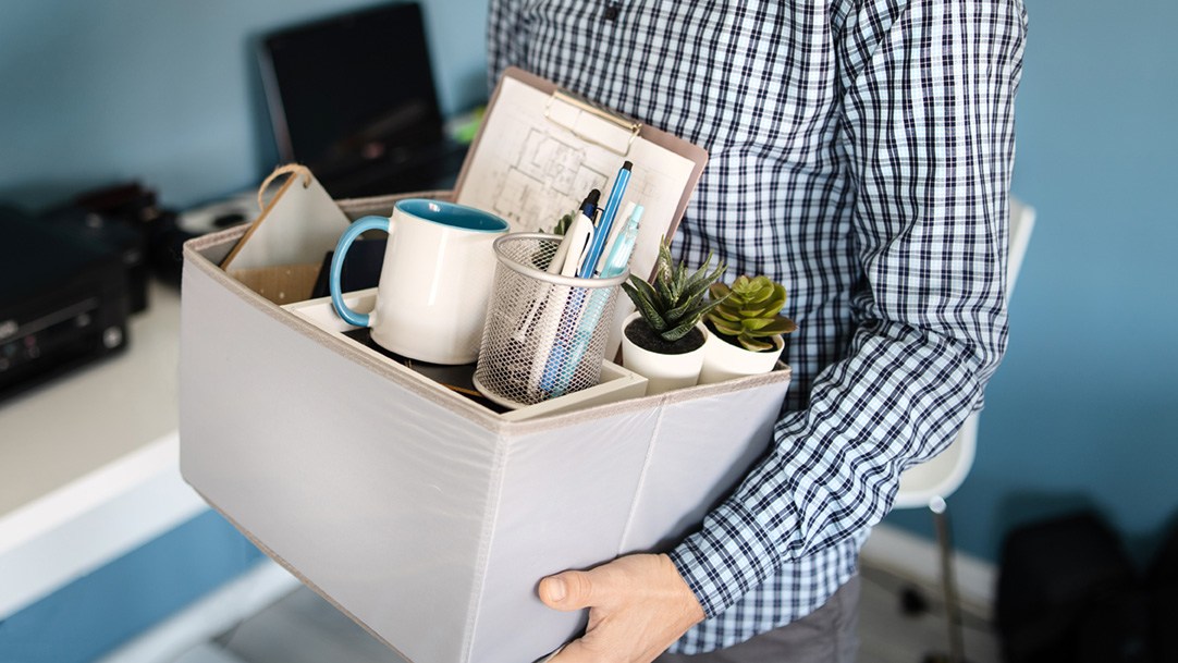 Ein Mann trägt eine Kiste mit Büroutensilien.