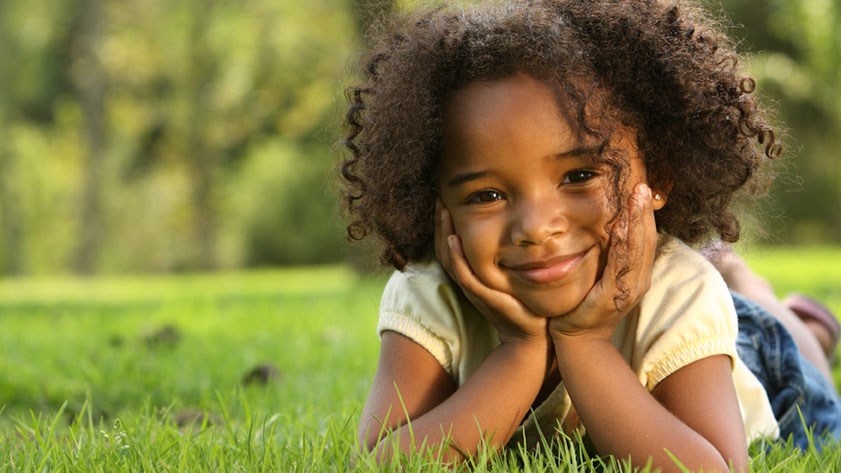 Kind liegt zufrieden im Park und lächelt: Nachdem es in der Familie Probleme gegeben hatte, kam es in Kurzzeitpflege.