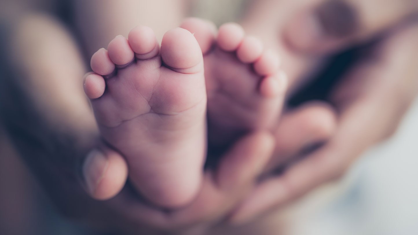 Elternteil hält Baby in den Händen: Die gemeinsam sorgeberechtigten Eltern bestimmen den Geburtsnamen.