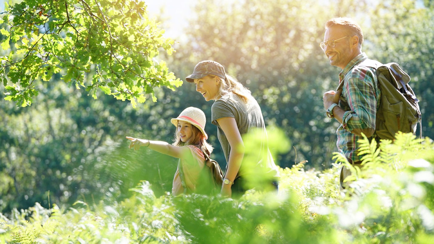 Pflegeeltern werden: Glückliche Pflegefamilie beim Urlaub in der Natur.