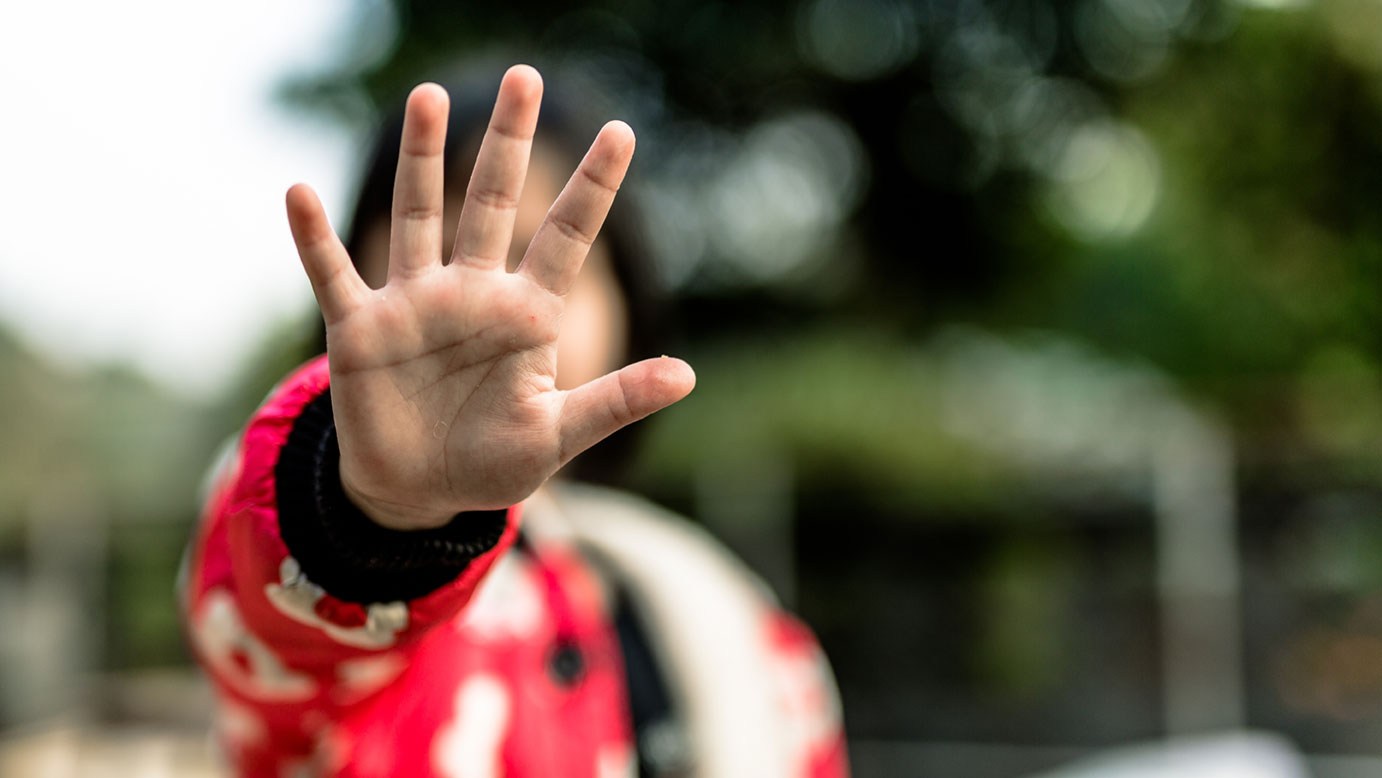 Kinder vor Missbrauch schützen: Minderjährige stellt sich mit der Hand schützend gegen einen Übergriffigen