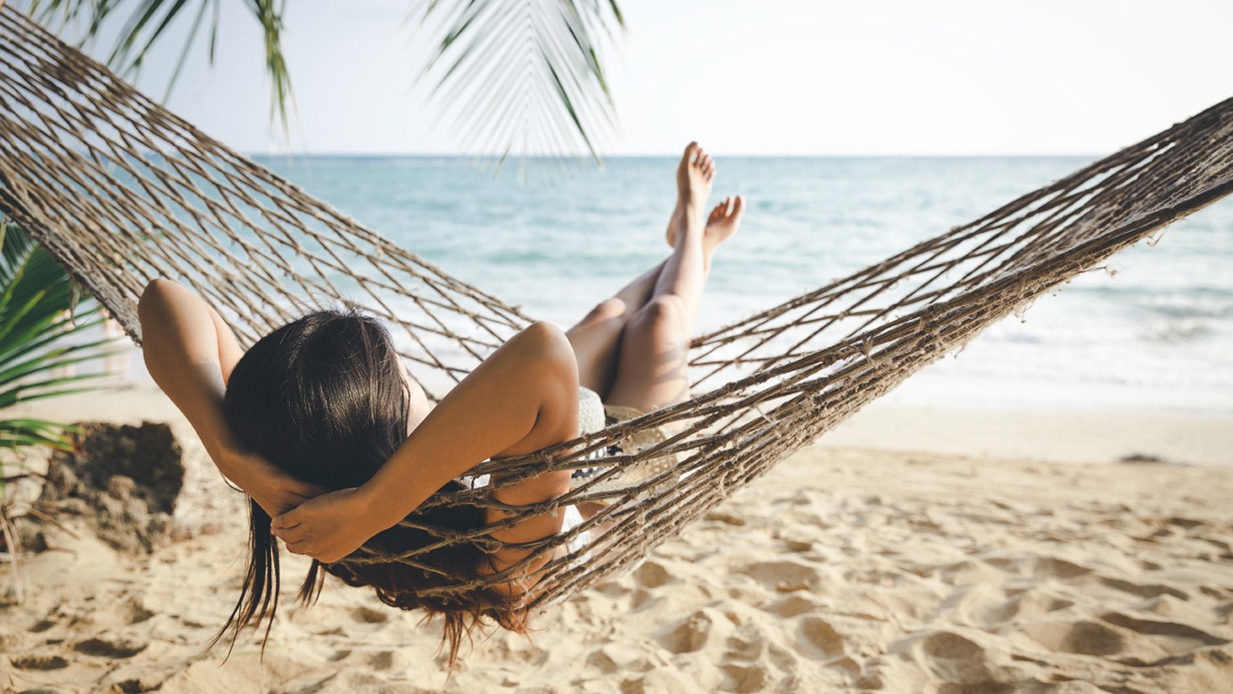 Eine Frau entspannt in einer Hängematte am Strand.